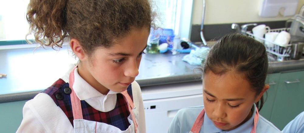 Two children preparing sushi from homegrown veges