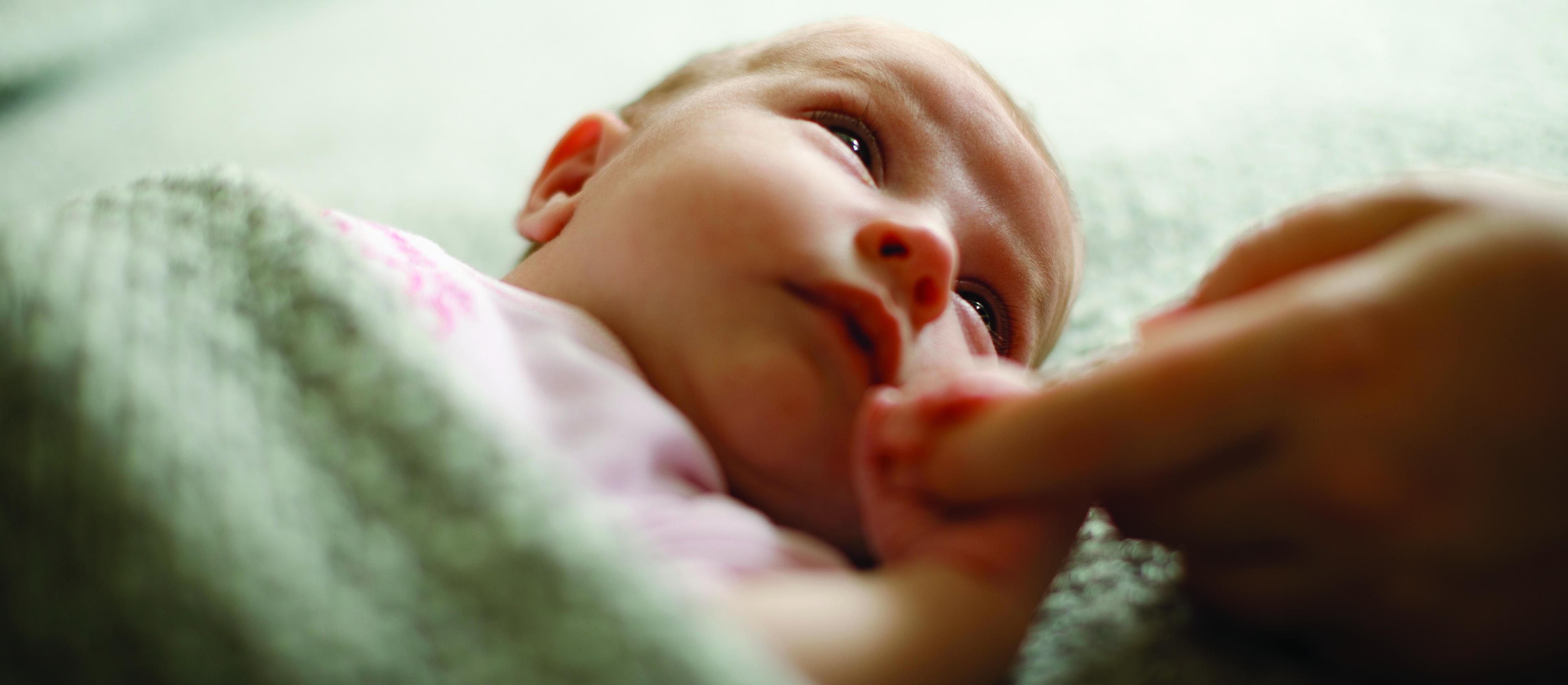 Baby holding mum's finger