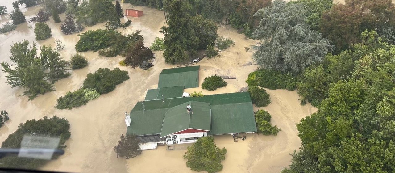 Aerial view taken from an NH90 helicopter of two people on the roof of their house to escape rising floodwaters caused by Cyclone Gabrielle