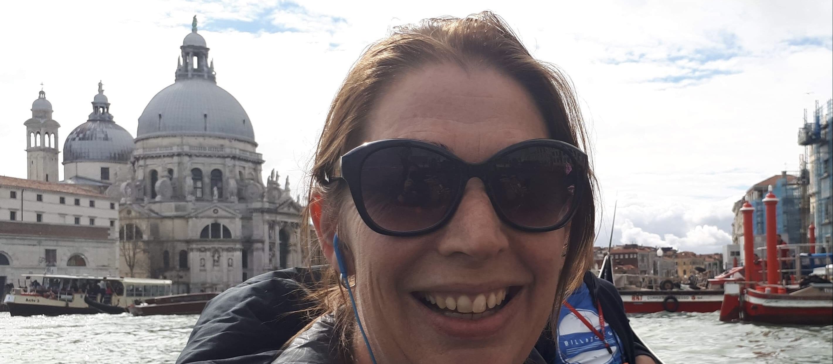 Lisa Hamblin on a boat with the Venice skyline behind her