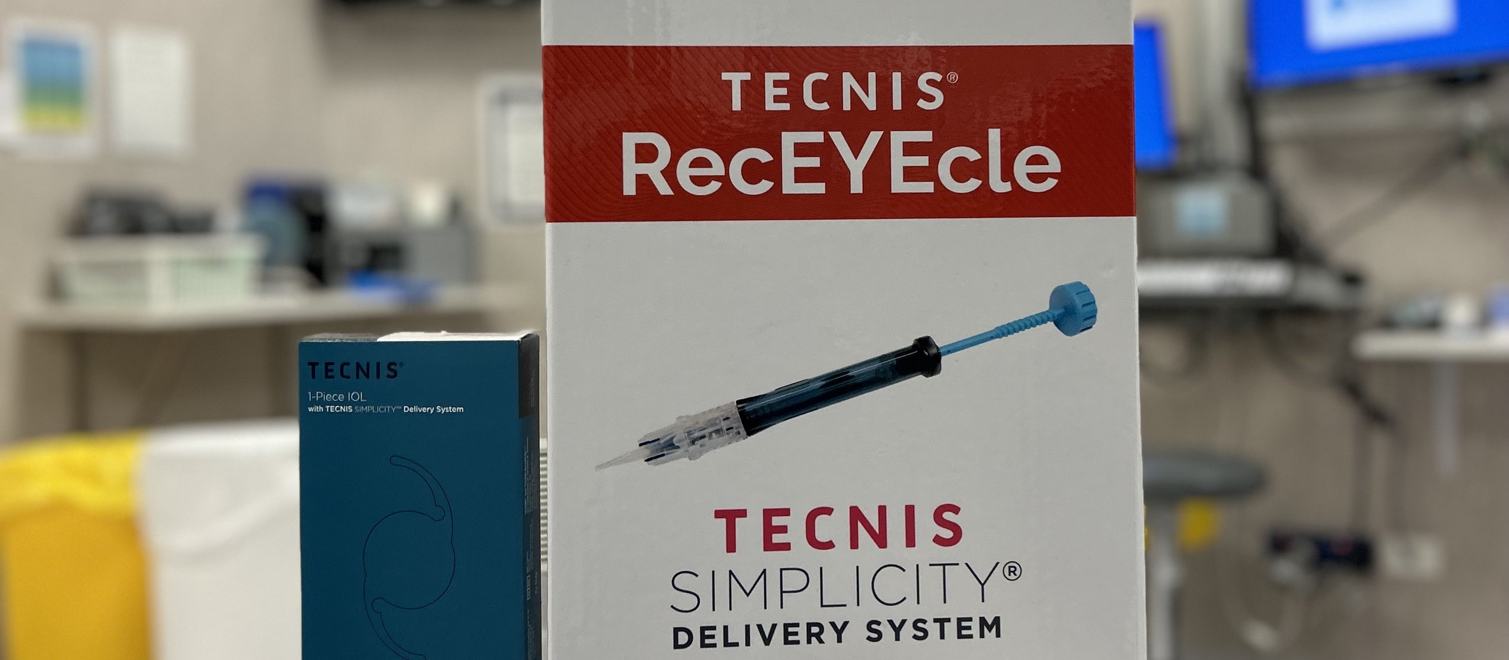 Image shows a recycling box on a surgical table with a medical syringe in front. Picture on box depicts a syringe with the words Tecnic RecEYEcle