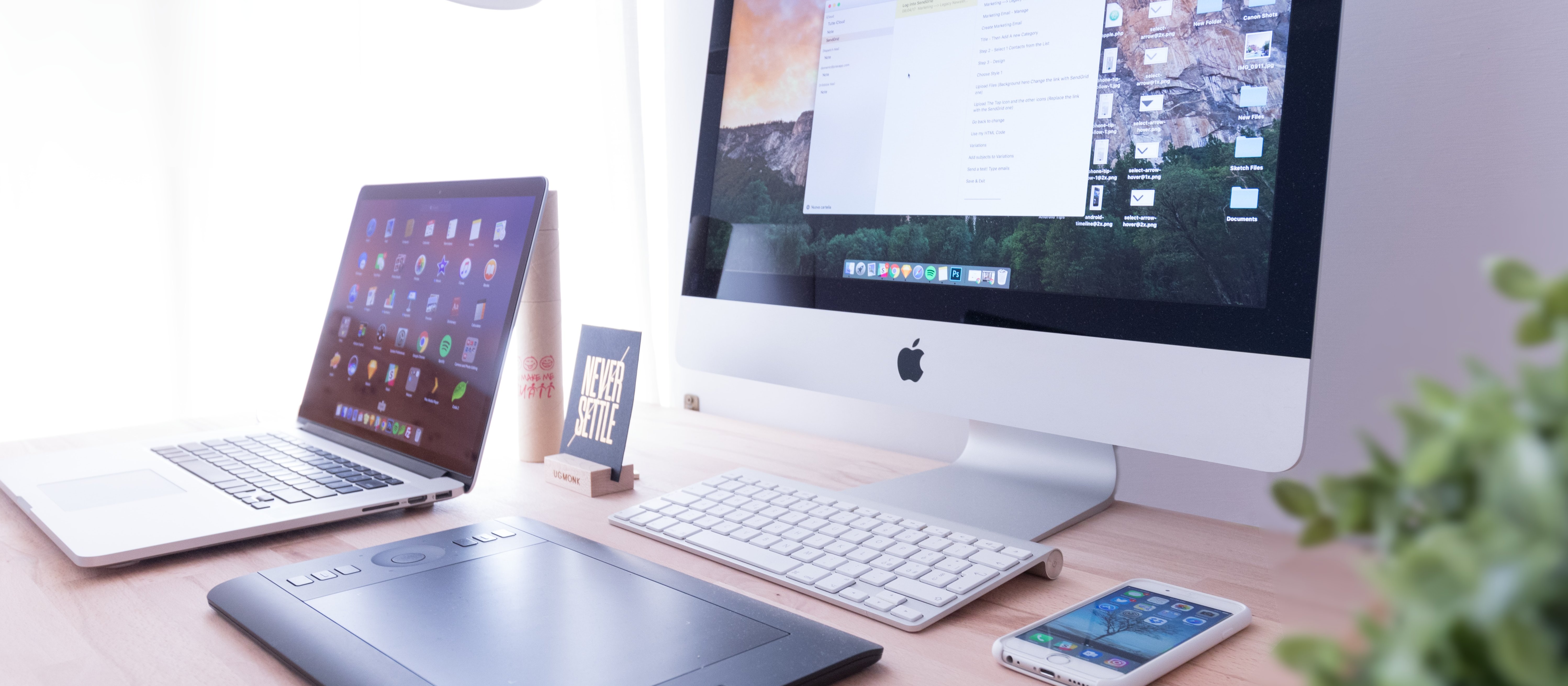 A desk with digital devices, including an Apple mac, a laptop, and a phone