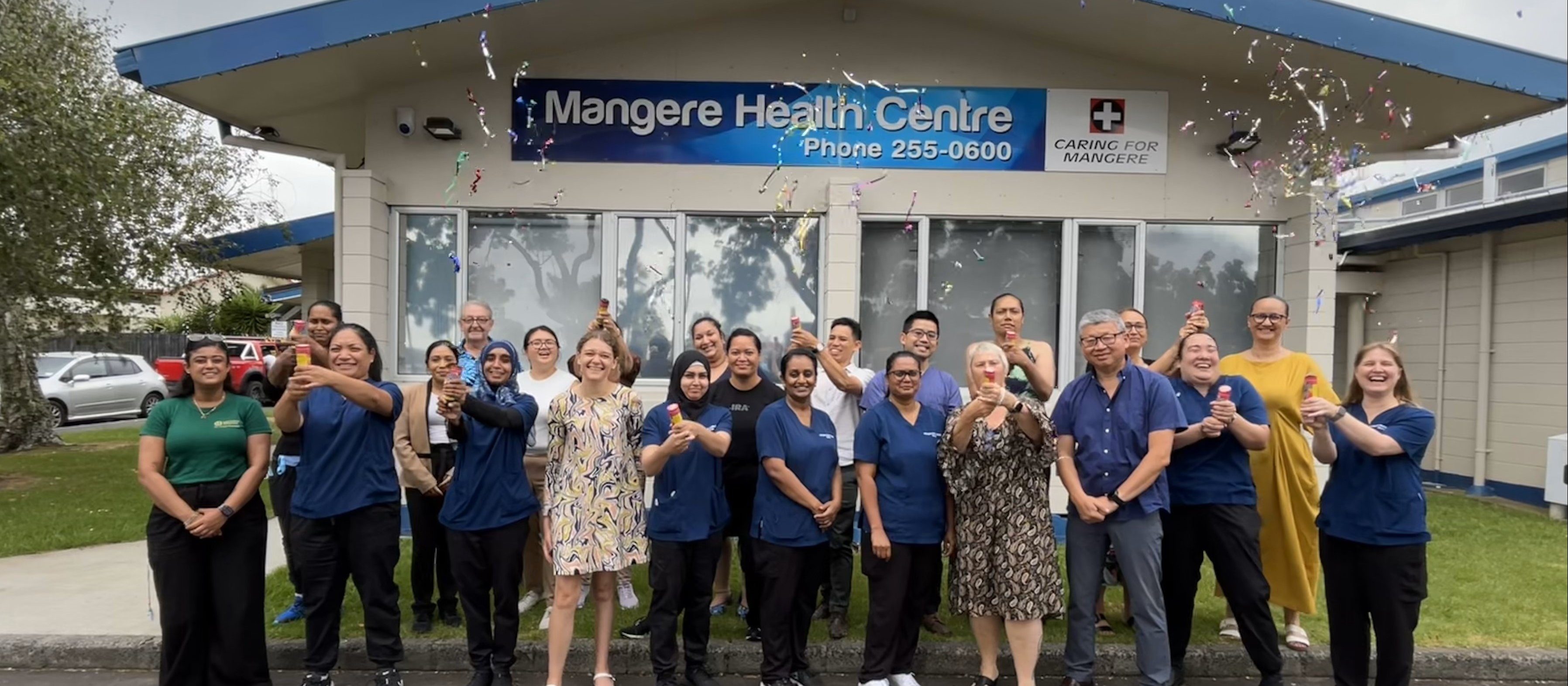 Staff stand outside Mangere Health Centre and let off party poppers