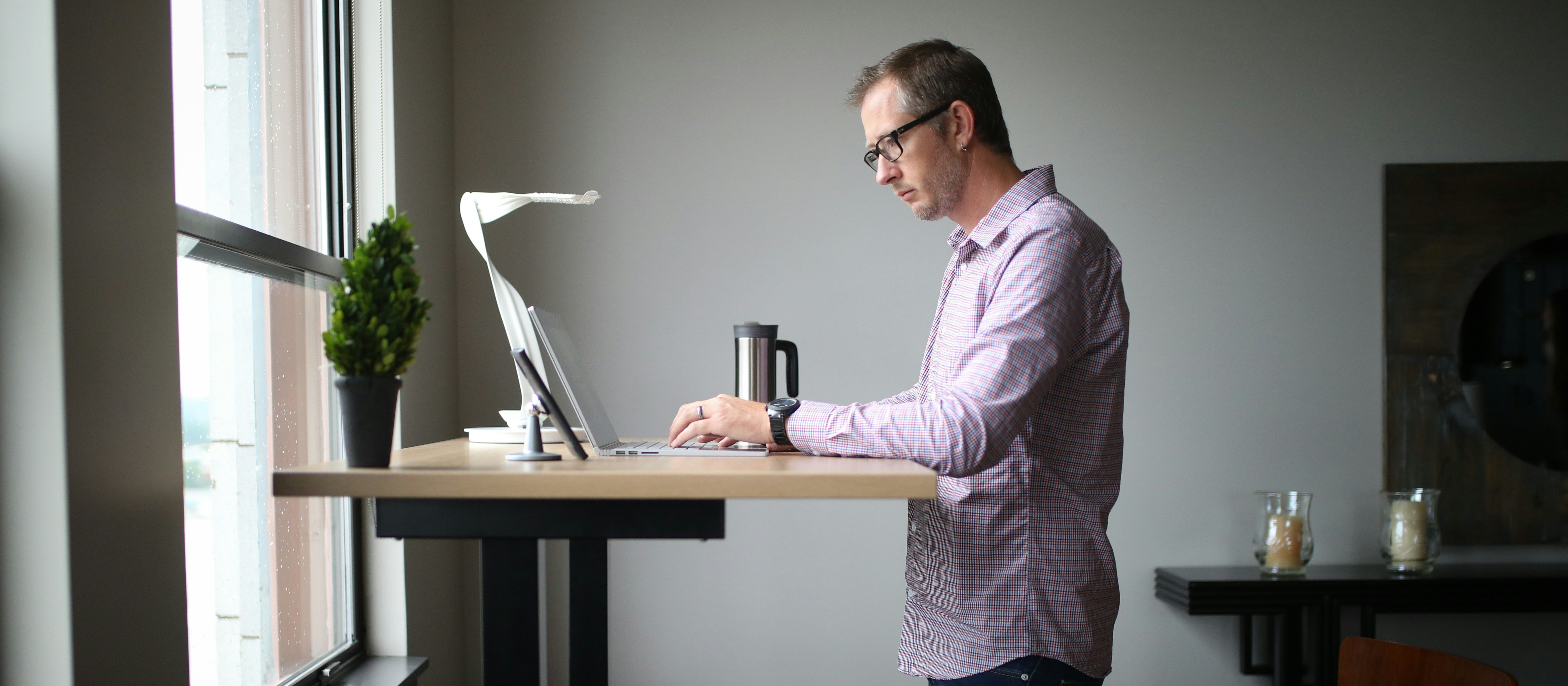 Man working at a standing desk, beside a window