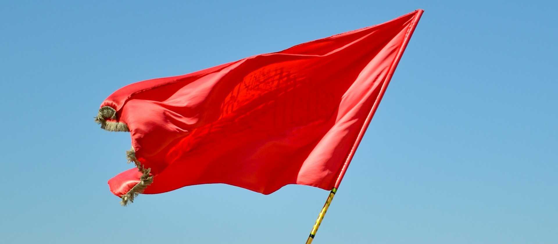 Red flag on pole daytime CR mhrezaa on Unsplash