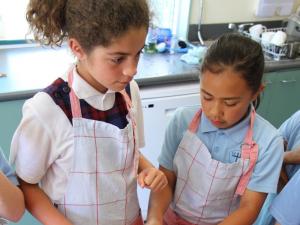 Two children preparing sushi from homegrown veges