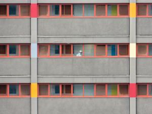  A worker in full PPE walks down the hallway of a locked down residential housing tower in North Melbourne, Victoria, Australia [Image: Chris McLay on Unsplash]