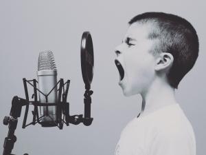 Kid speaking into microphone, microphone, Unsplash Jason Rosewell