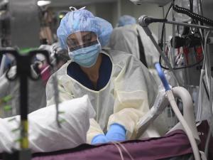 A nurse preparing a COVID-19 patient for a procedure in intensive care, April 2020 [photo: Sara Eshleman, US Navy]