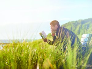 Man reading a book in a field_Ben White on Unsplash