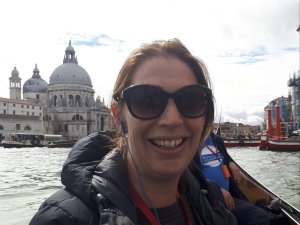 Lisa Hamblin on a boat with the Venice skyline behind her