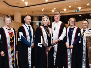 Photo shows RNZCGP distinguished fellows standing in a line, wearing gowns, and smiling at camera