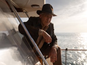 Older man in fedora on yacht overlooking glistening ocean