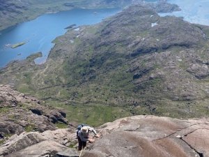 A man climbing a rock face on a sunny day