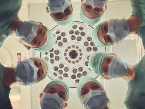 Faces of surgeons wearing masks and standing in a circle looking down