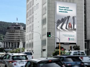 Billboard for Aged Care Association campaign on side of building with traffic in front and Parliament buildings behind