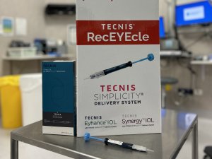 Image shows a recycling box on a surgical table with a medical syringe in front. Picture on box depicts a syringe with the words Tecnic RecEYEcle