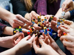 Hands hold Lego figures [Vlad Hilitanu on Unsplash]