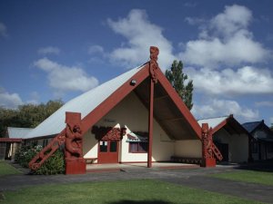 Front of Papakura Marae, viewed slightly from the side. Blue sky, with some white clouds in background