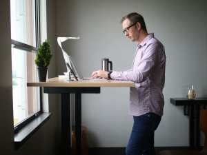 Man working at a standing desk, beside a window