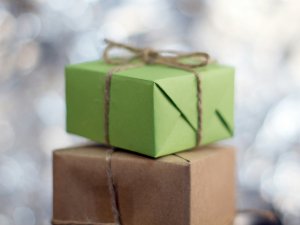 A brown paper parcel wrapped in string, with a green parcel sitting on top 